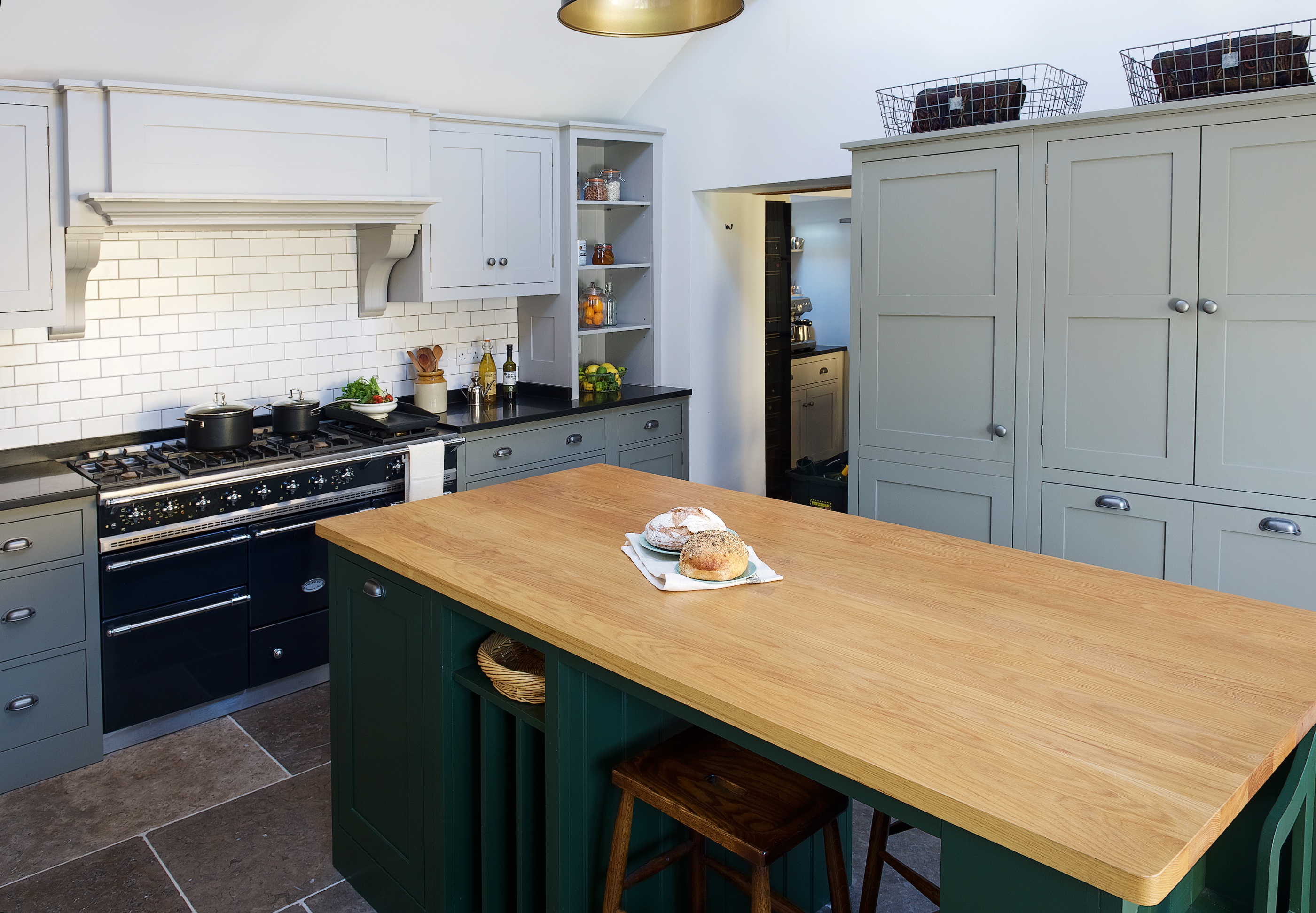 Bespoke shaker kitchen handpainted in Little Greene with a large island with oak worktop and white metro tile splashaback.