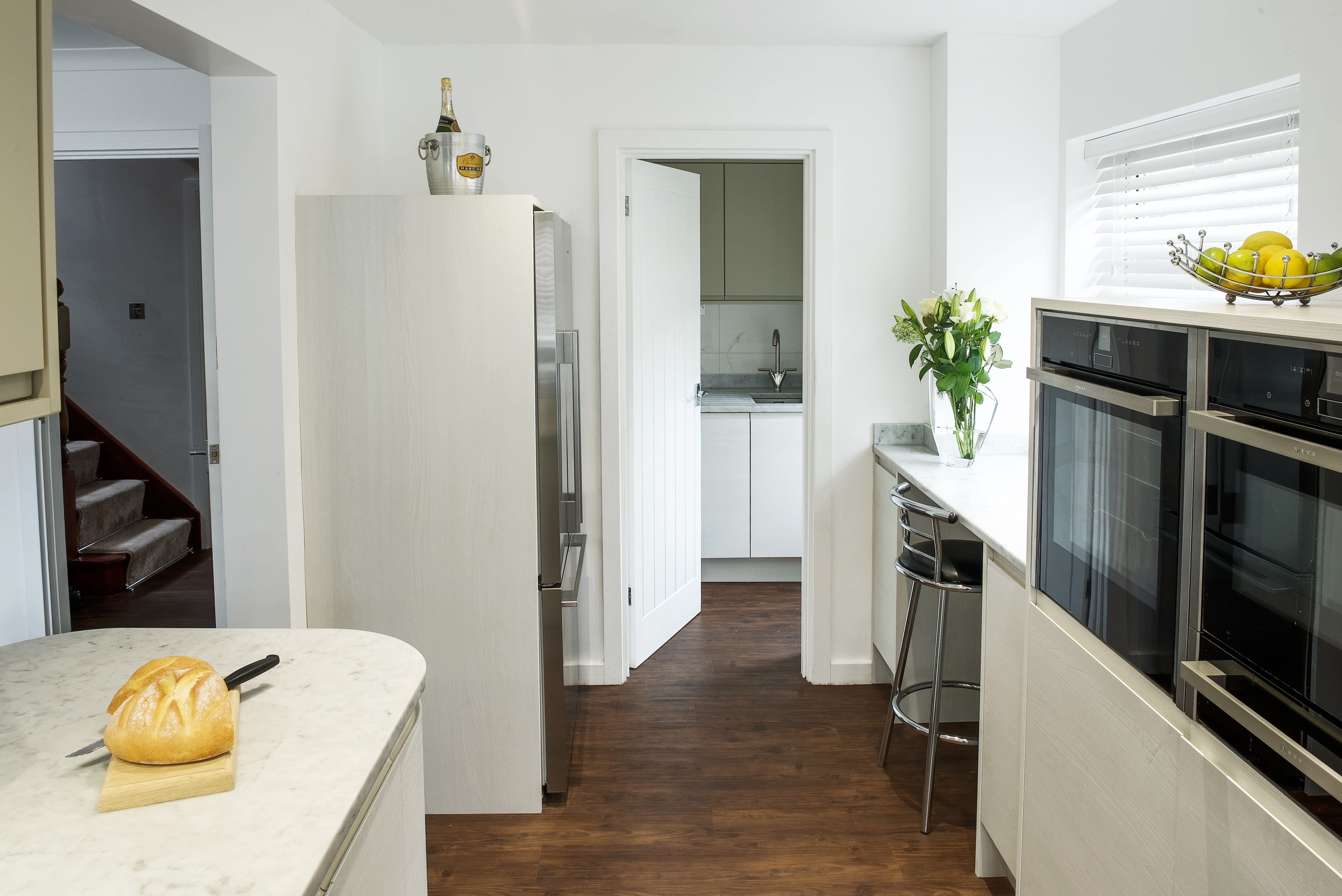 White contemporary kitchen with Neff slide under ovens and and a Fisher Paykel french door fridge freezer.