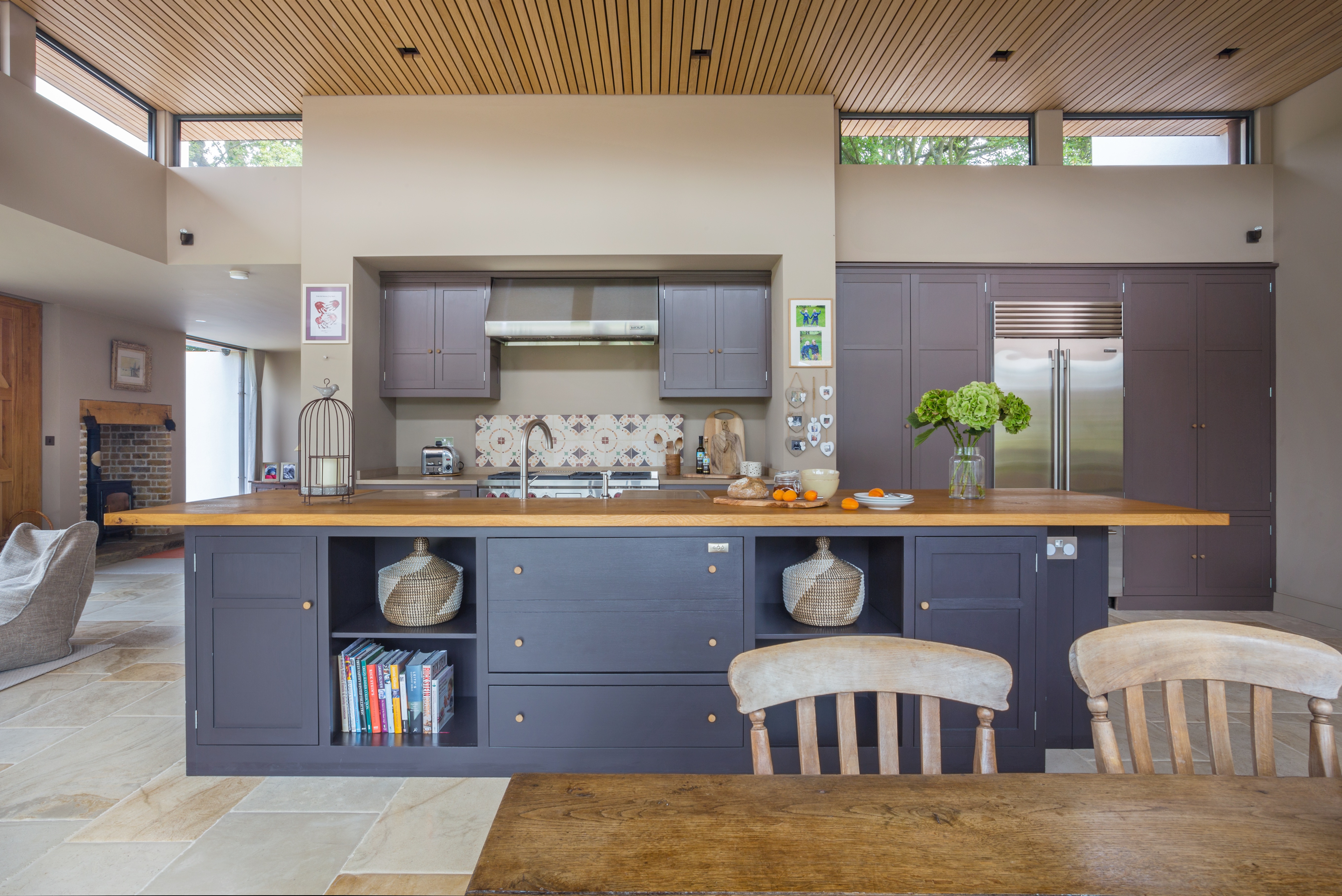 Handpainted cabinets in Farrow & Ball Clay 244 with rustic oak worktop on kitchen island and a Subzero fridge ICBBI 36UFDID.