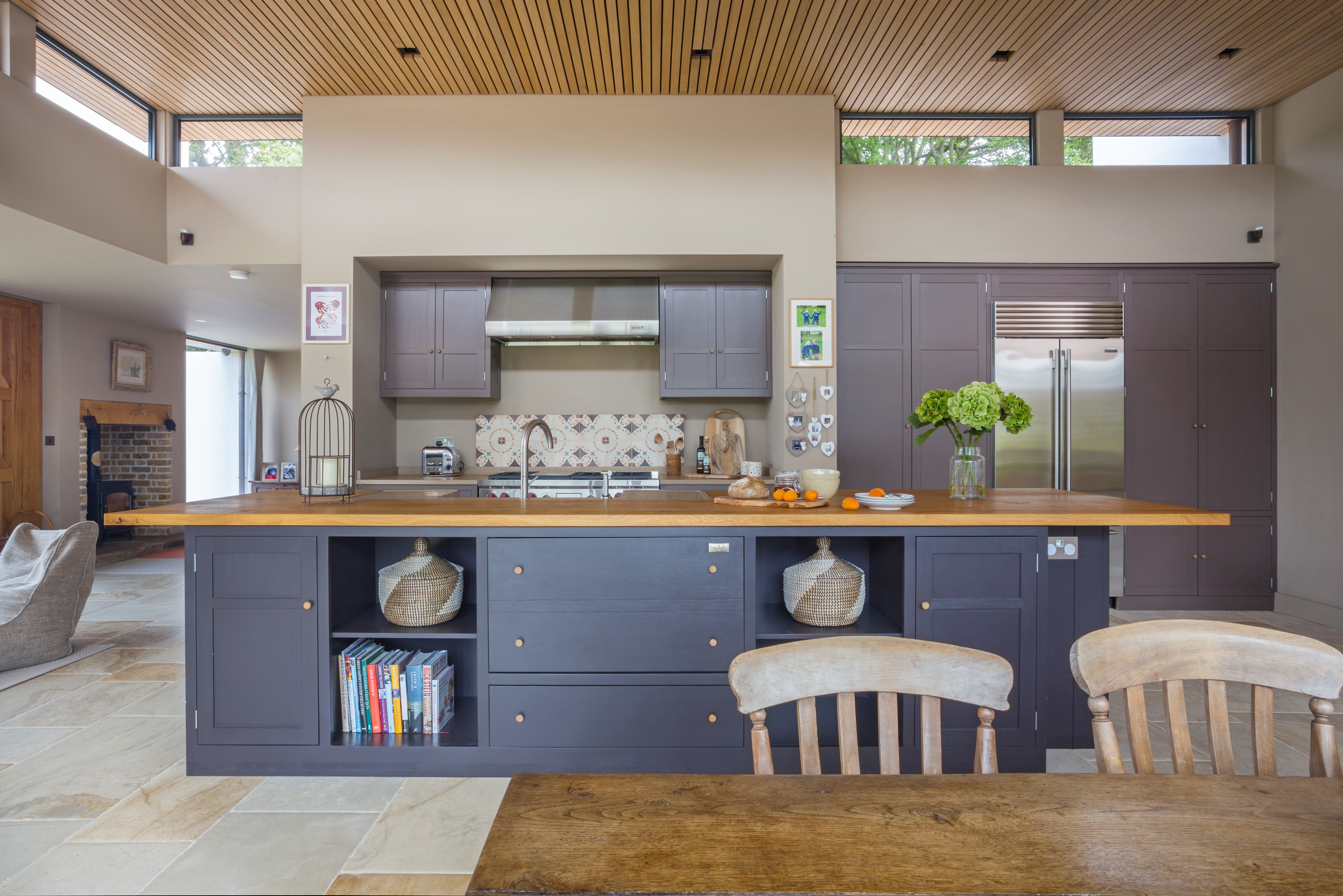Handpainted cabinets in Farrow & Ball Clay 244 with rustic oak worktop on kitchen island and a Subzero fridge ICBBI 36UFDID.