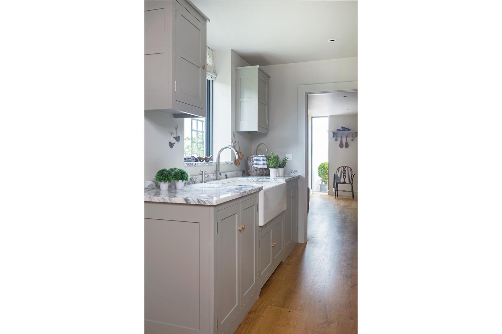 Plain shaker utility room in Farrow and Ball Harwick with polished Arrabascatta marble worktops and a reclaimed butler sink.