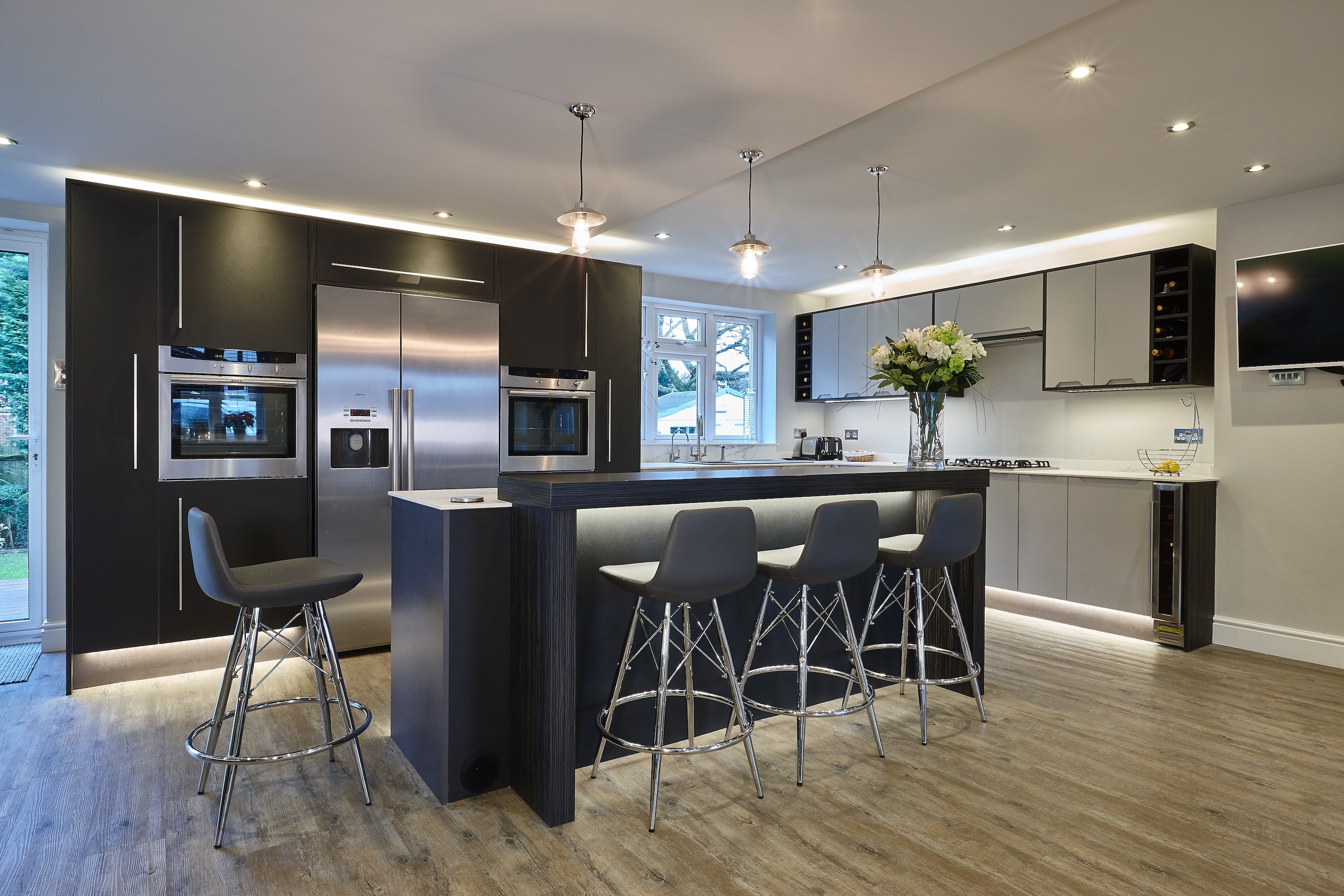 Bespoke contemporary CK kitchen with leather and grey cabinets and a large walnut wood island and stainless steel appliances.