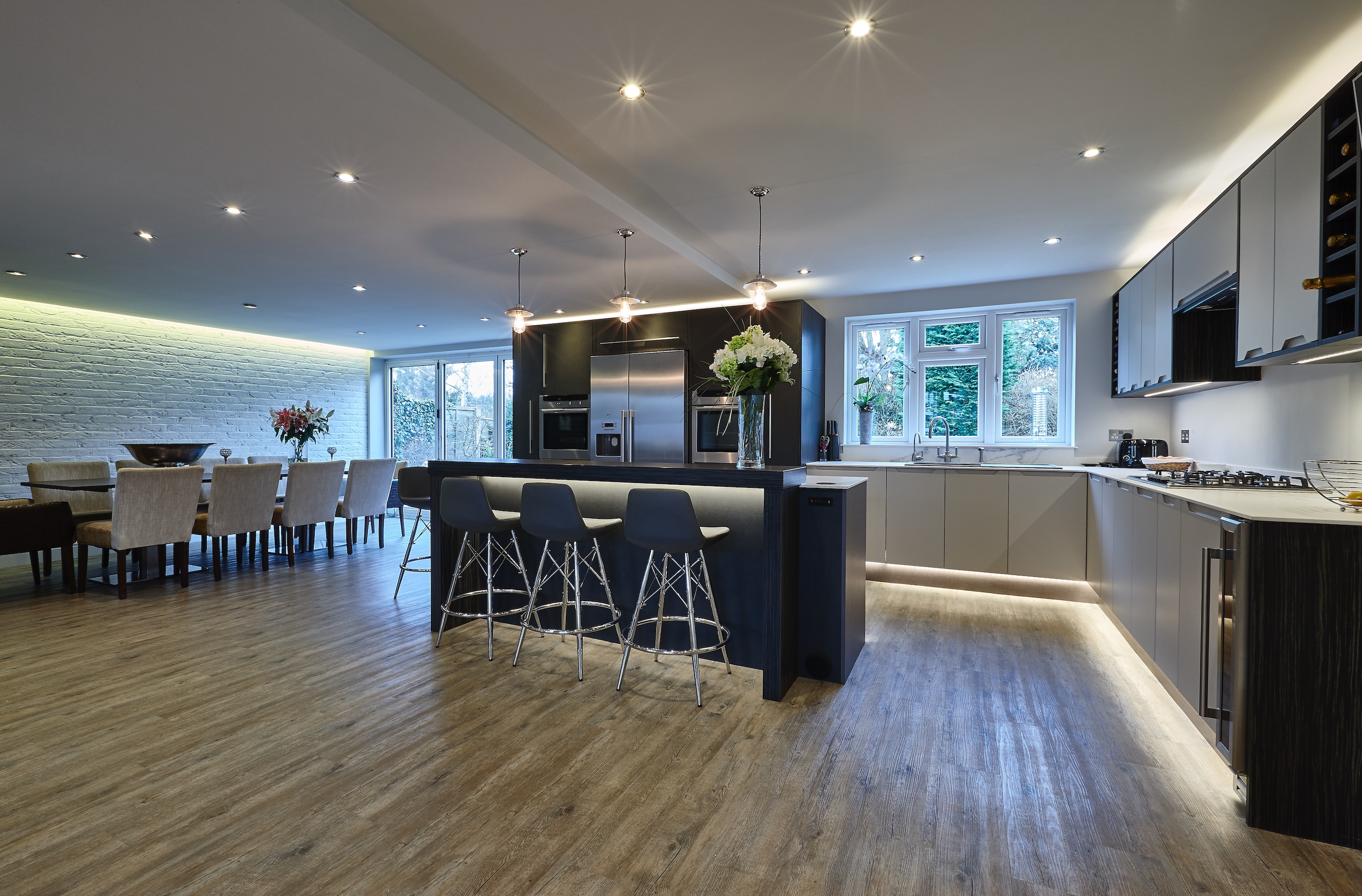 Bespoke contemporary CK kitchen with leather and grey cabinets and a large walnut wood island and stainless steel appliances.