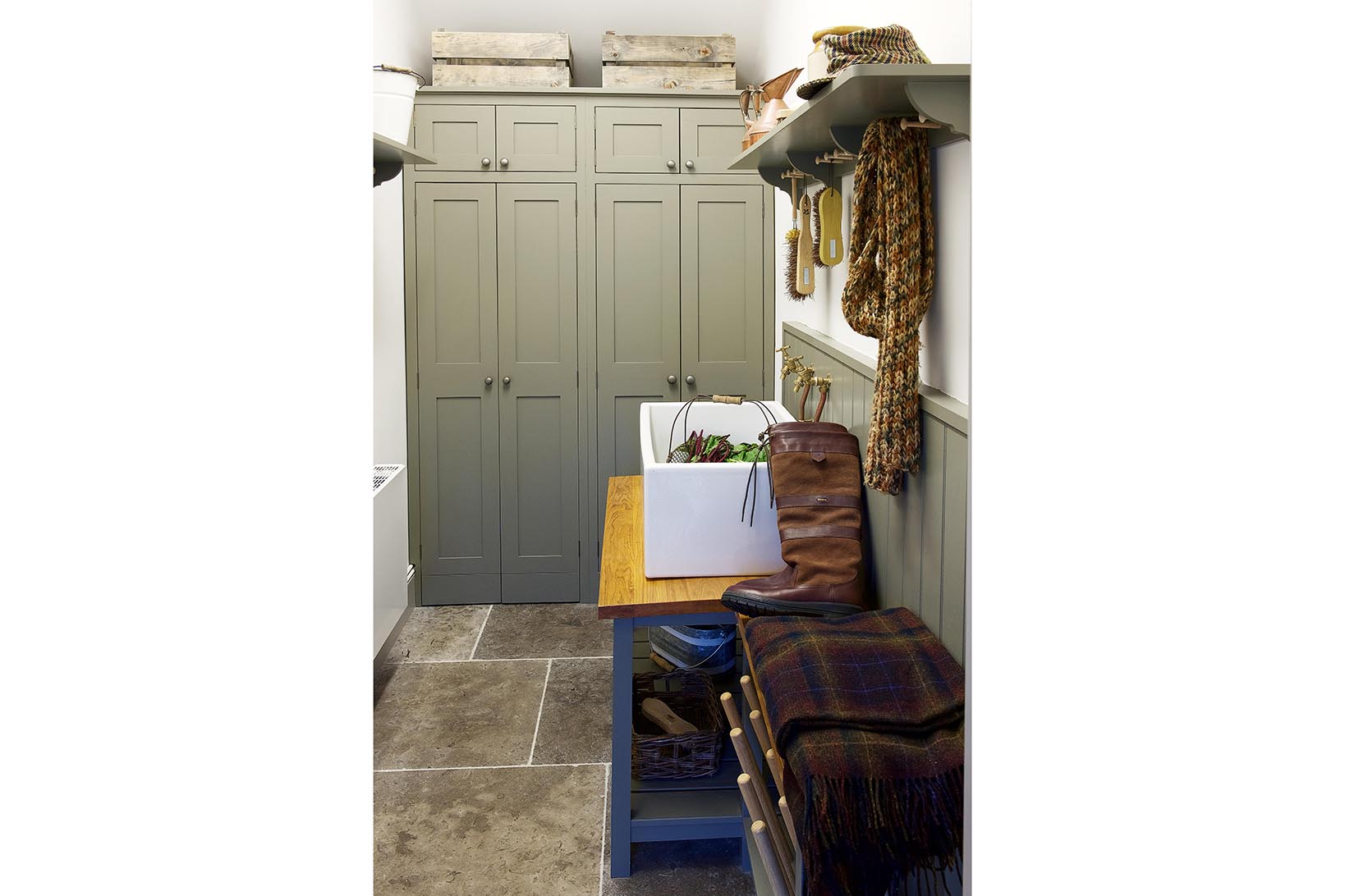 Bespoke shaker style utility room painted in Grey Moss with a Perrin & Rowe butler sink and brass taps and a shelf with pegs above.