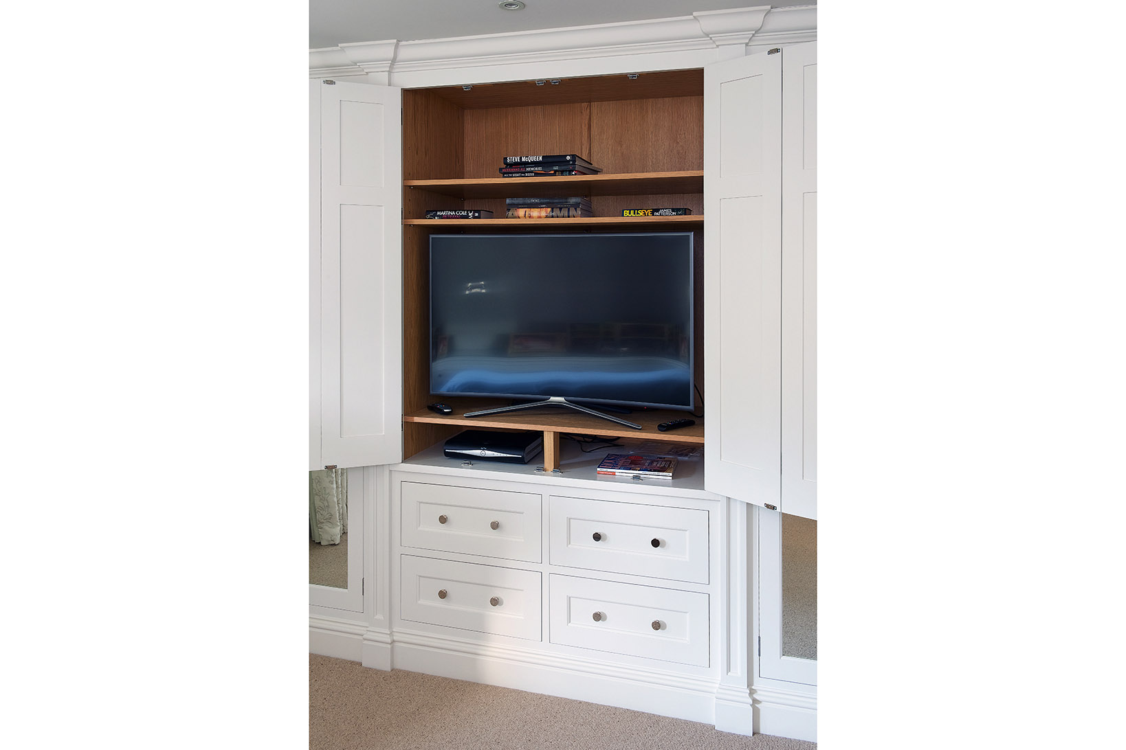 Open built in wardrobes painted in Zoffany Quarter Paris Grey with polished chrome handles and mirrored panels with TV inside.
